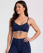 Woman wearing a navy blue sports bra and leggings on a light gray background
