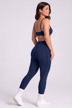 Woman wearing a navy blue sports bra and leggings set on a white background