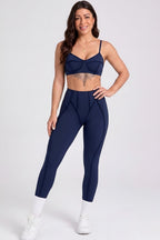 Woman wearing a navy blue sports bra and leggings set on a white background