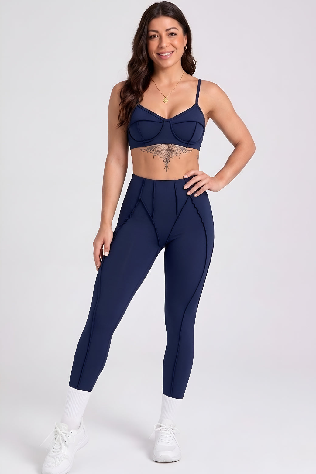 Woman wearing a navy blue sports bra and leggings set on a white background