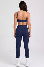 Person wearing a navy sports bra and leggings set on a white background