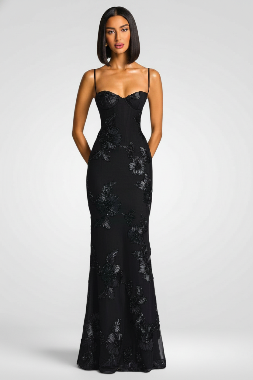 Woman wearing a black strapless gown with floral patterns on a white background