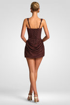 Woman wearing a brown dress with a lace-up back on a white background