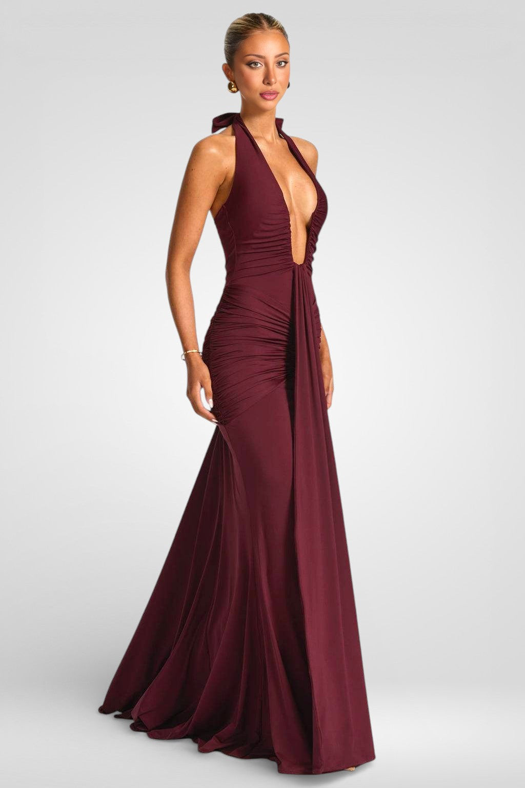 Woman wearing a burgundy evening gown with a plunging neckline on a white background