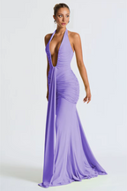 Woman wearing a long purple dress with a halter neck on a white background