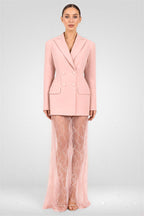 Woman wearing a pink suit with sheer pants on a white background