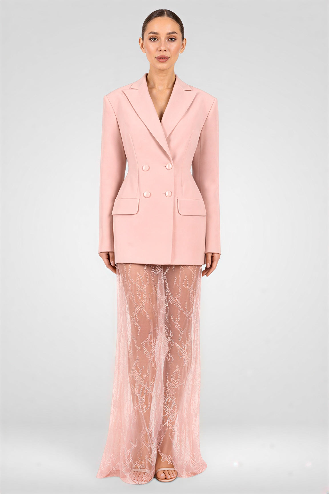 Woman wearing a pink suit with sheer pants on a white background