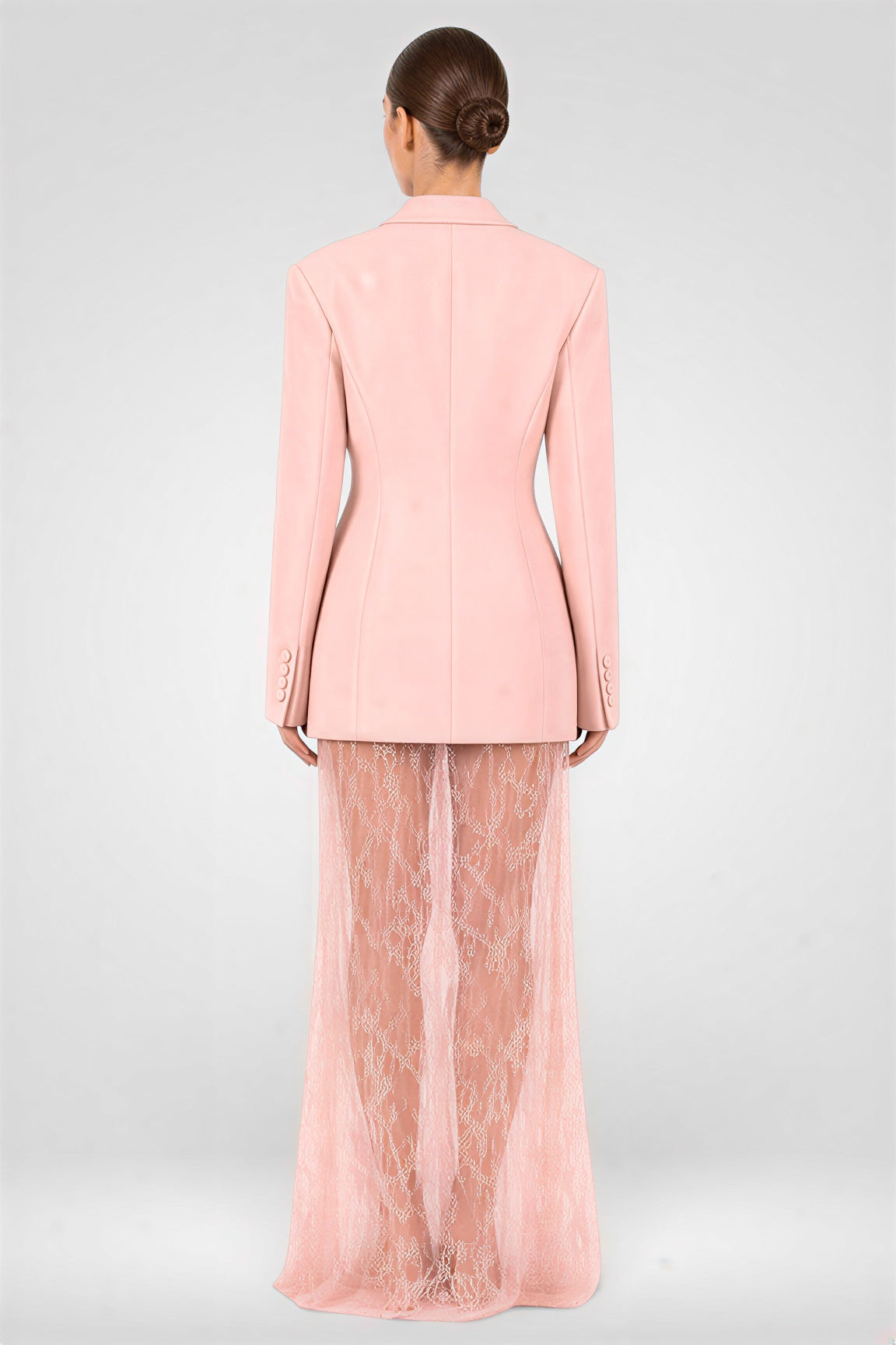Person wearing a pink suit with sheer pants on a light gray background