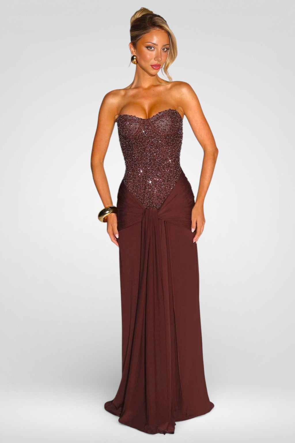 Woman wearing a strapless brown evening gown with sequin bodice on a white background