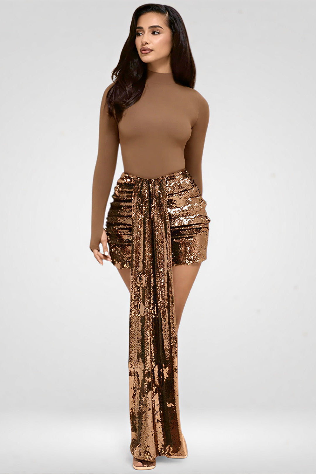 Woman wearing a brown top and sequin skirt on a white background