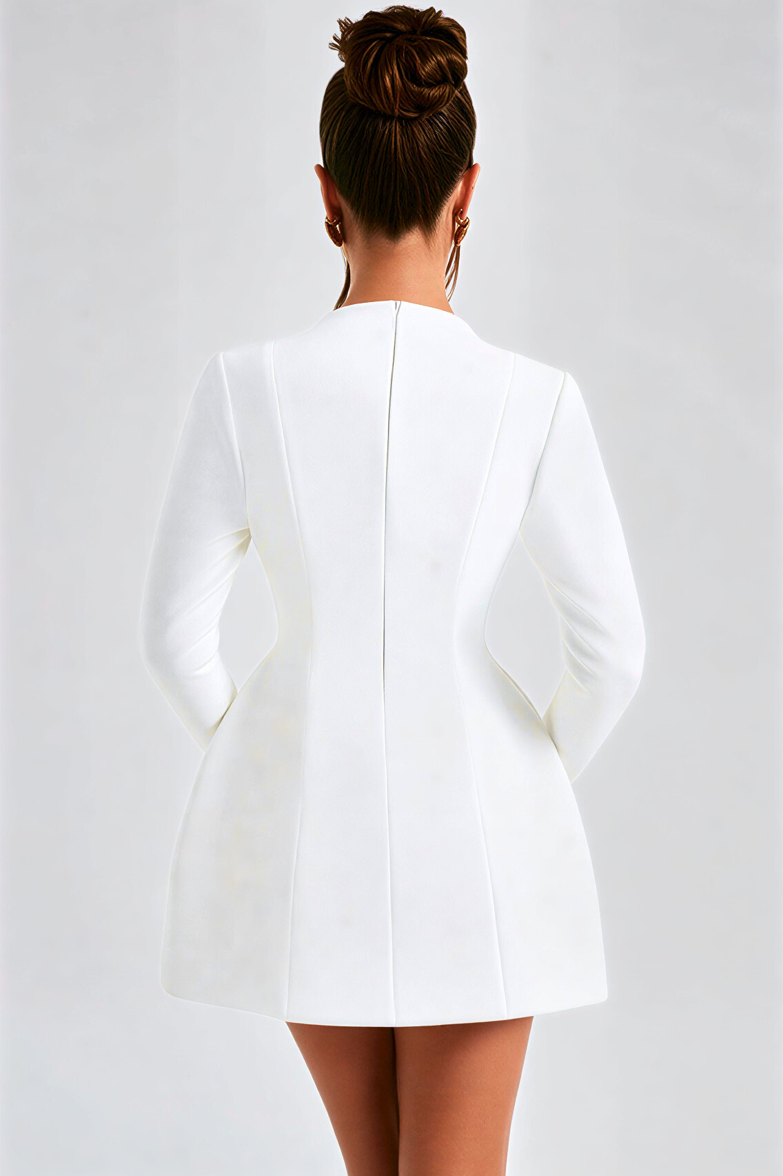 Person wearing a white blazer against a plain background