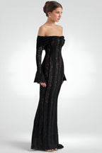 Woman wearing a black off-shoulder gown with long sleeves on a white background