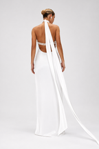 Woman wearing a white wedding dress with a long train on a plain background