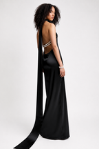 Woman wearing a black evening gown with a long train on a white background