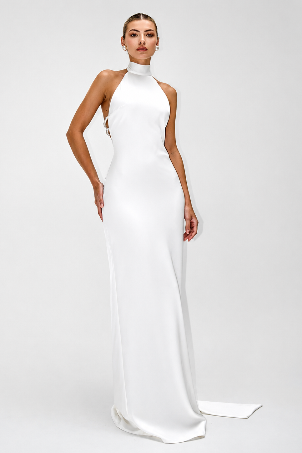 Woman wearing a white halter neck gown on a plain background