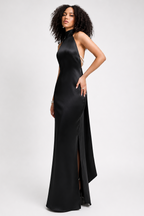 Woman wearing a black evening gown with a high slit on a white background