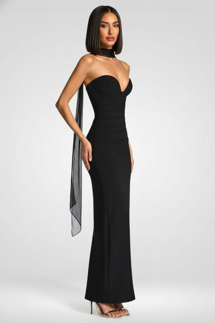 Woman wearing a black strapless gown with a slit on a white background