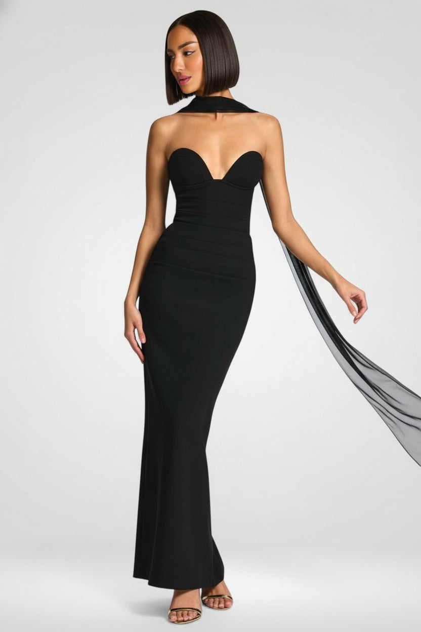 Woman wearing a black strapless gown with a flowing train on a white background