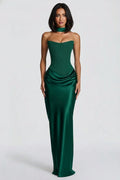 A woman modeling a strapless emerald green satin gown with a sweetheart neckline, structured corset-style bodice, ruched waist, and a matching choker, photographed against a light gray studio background.