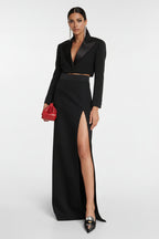 Black outfit with a high slit skirt and red handbag on a white background