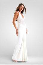 Woman wearing a white halter neck gown on a plain background