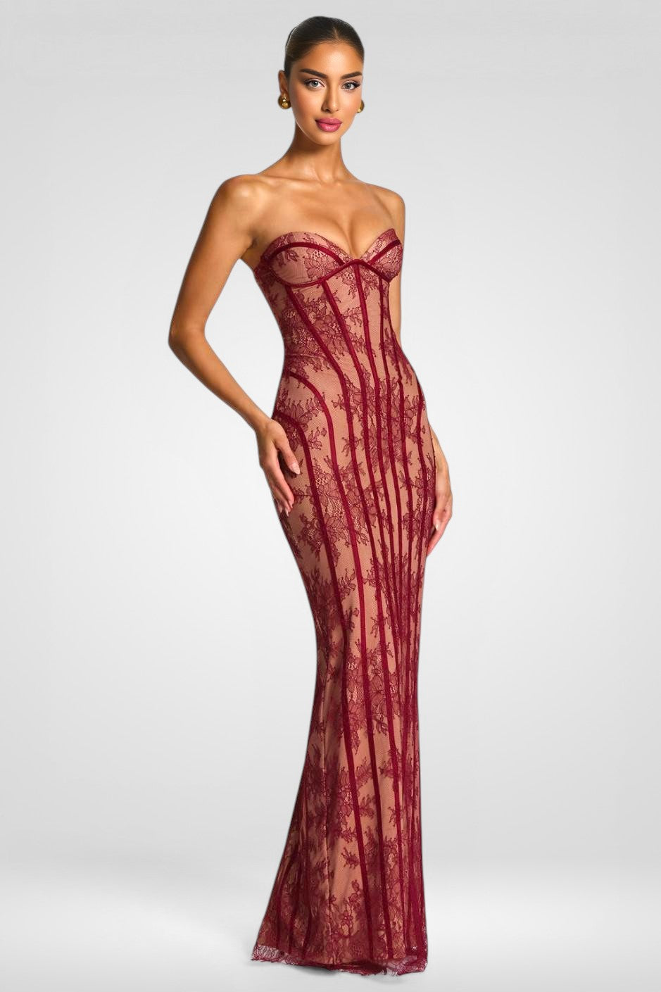 Woman wearing a strapless red lace evening gown on a white background