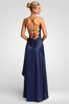 Woman wearing a navy blue evening gown with a strappy back design on a light gray background