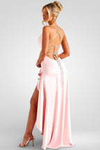 Woman wearing a pink evening gown with a strappy back design on a white background