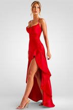 Woman wearing a red dress with a high slit on a gray background