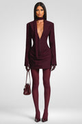 Woman wearing a burgundy suit with matching accessories on a white background
