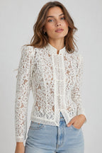 Woman wearing a white lace blouse with blue jeans on a gray background