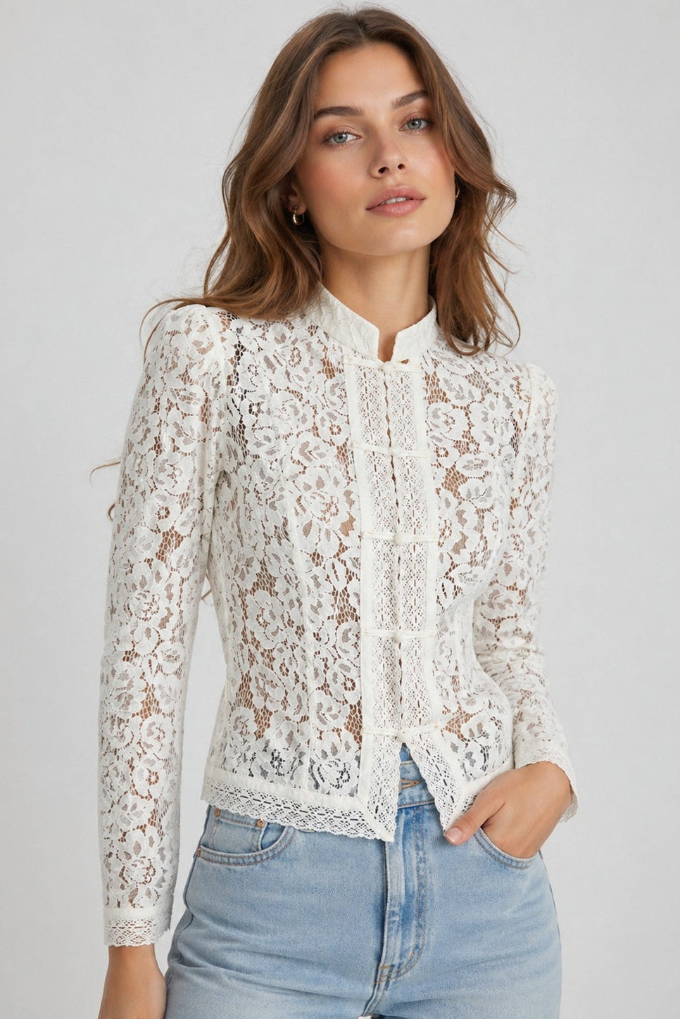 Woman wearing a white lace blouse with blue jeans on a gray background