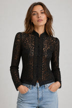 Woman wearing a black lace jacket with a plain background