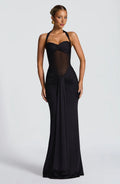 Woman wearing a black evening gown with sheer panels on a white background