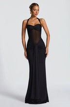 Woman wearing a black evening gown with sheer panels on a white background