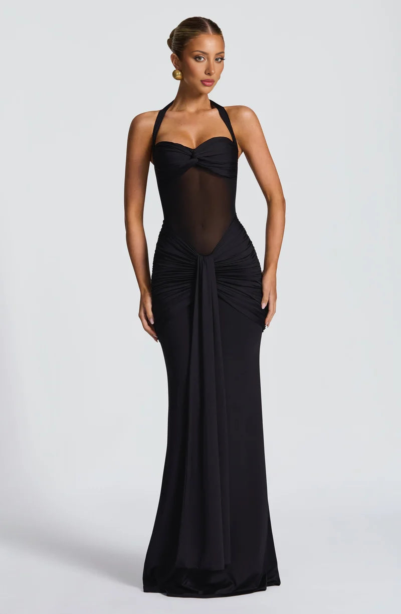 Woman wearing a black evening gown with sheer panels on a white background