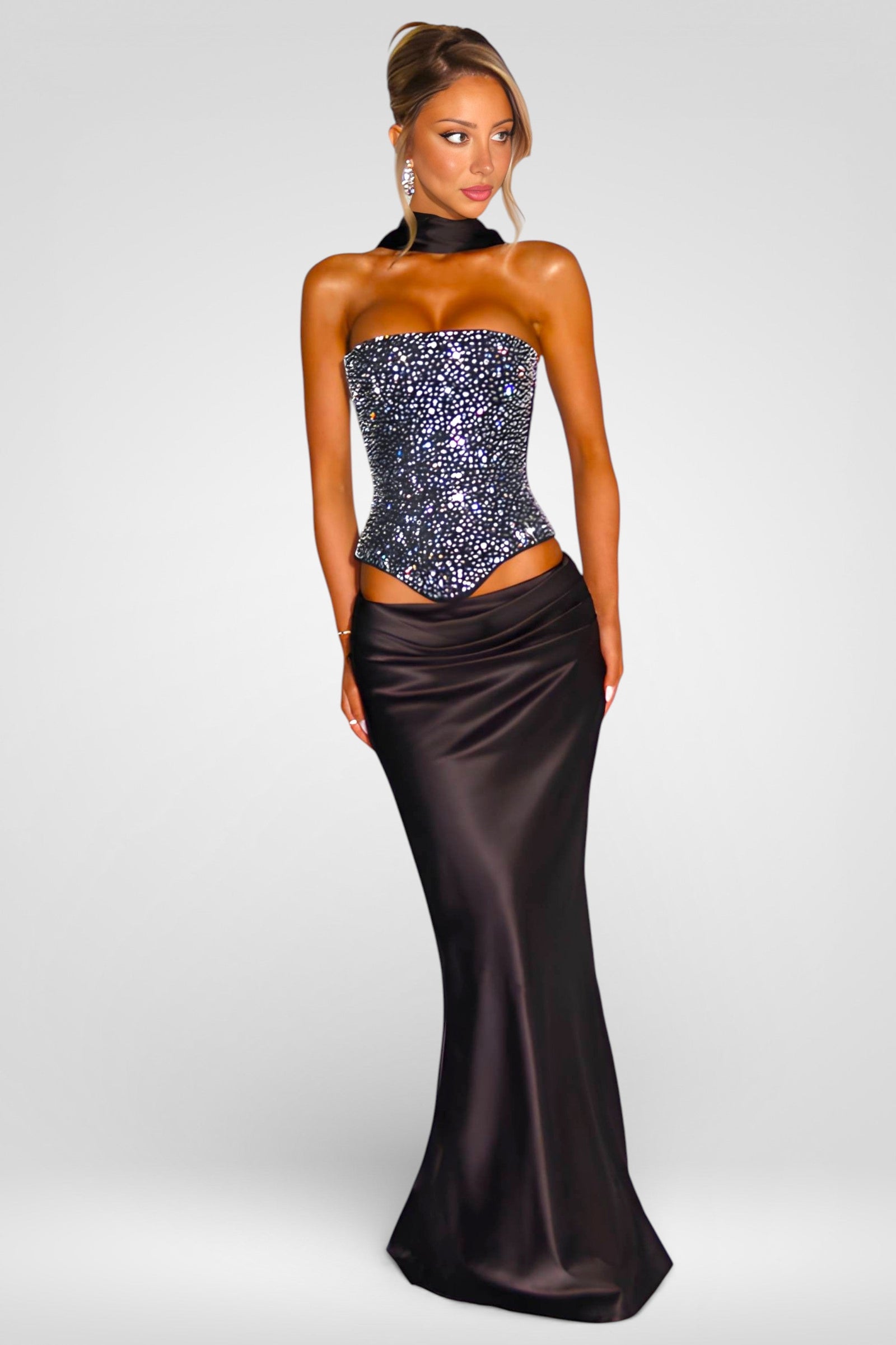 Woman wearing a strapless sequined top and long satin skirt on a white background