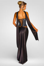 Woman wearing a black evening gown with a sheer overlay on a white background