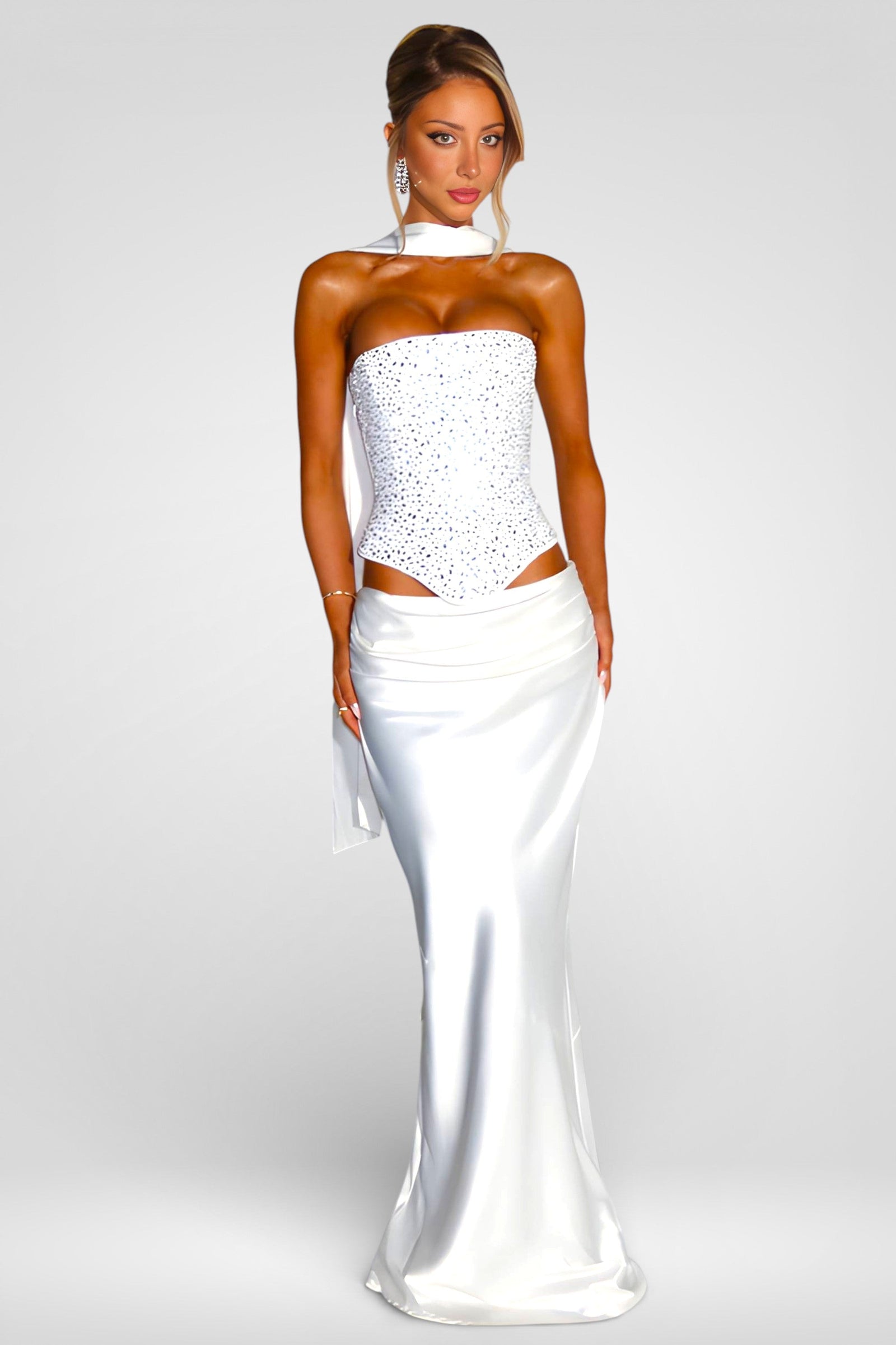 Woman wearing a white strapless gown with cut-out design on a gray background