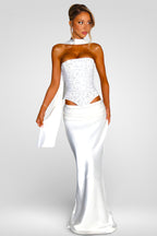 Woman wearing a white strapless gown with cut-out design on a plain background