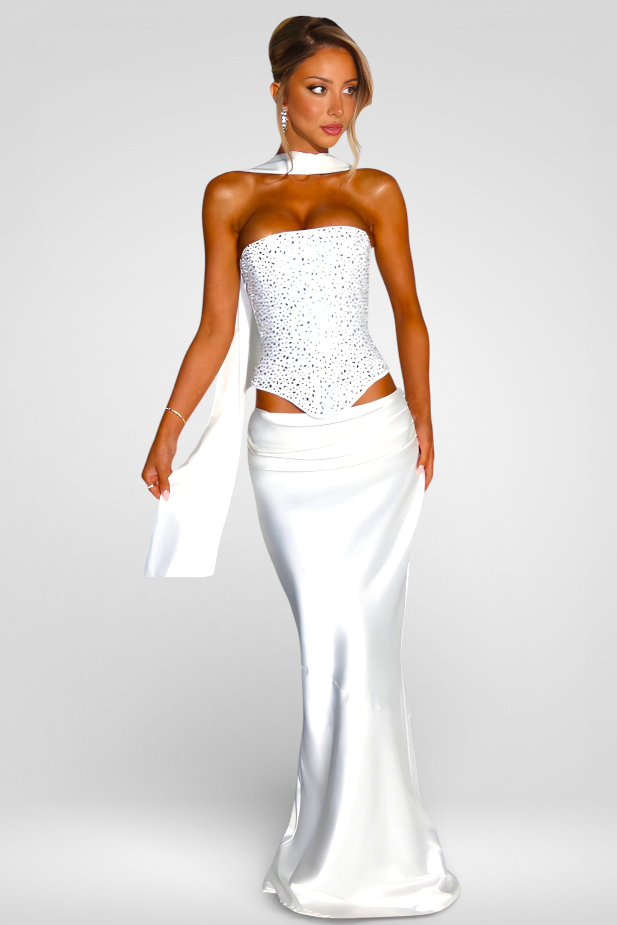 Woman wearing a white strapless gown with cut-out design on a plain background