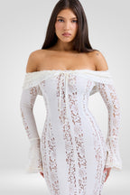 Woman wearing a white lace off-shoulder dress on a plain background