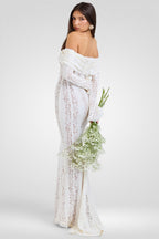 Woman in a white lace dress holding flowers on a plain background