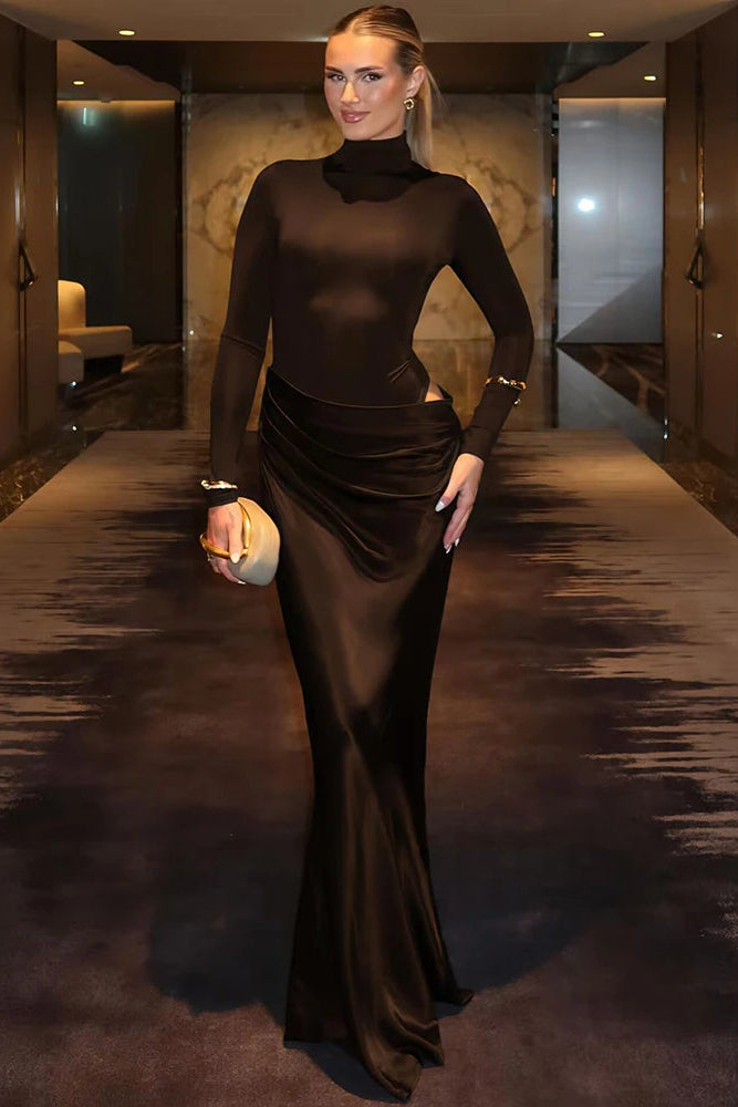 Woman in a brown evening gown standing in an elegant interior setting.