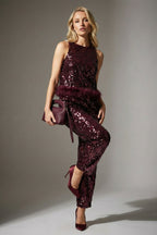 Woman wearing a burgundy sequin outfit with matching shoes and clutch against a gray background