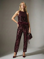 Woman wearing a sparkly burgundy jumpsuit against a neutral background