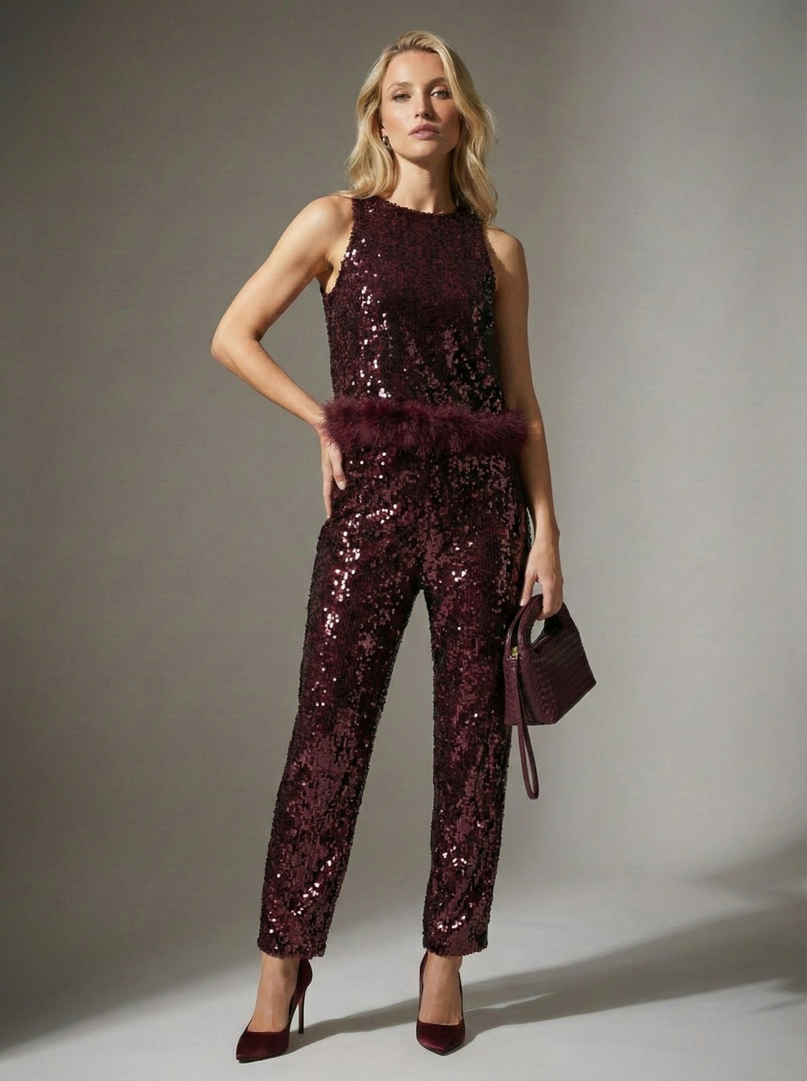 Woman wearing a sparkly burgundy jumpsuit against a neutral background