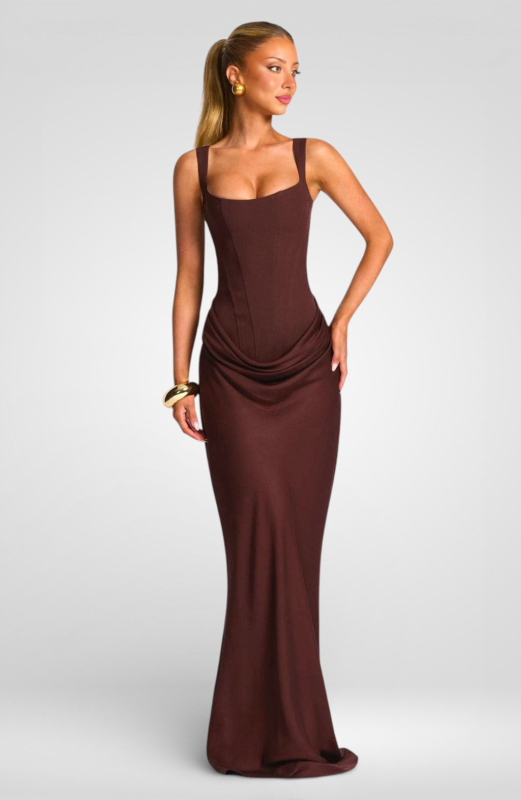 Woman wearing a brown evening gown on a plain background