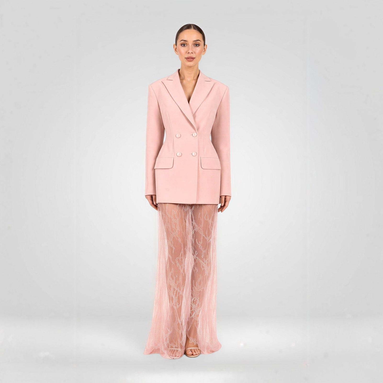 Woman wearing a pink suit with sheer pants on a light gray background